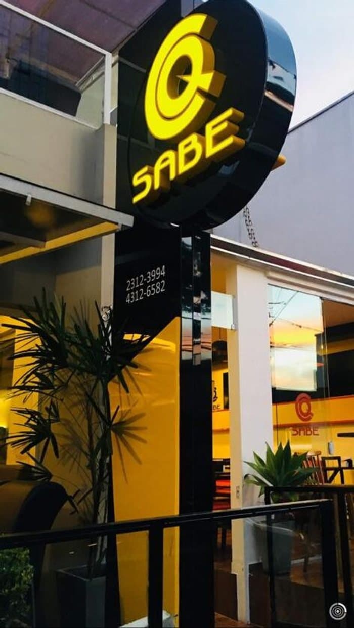 Fachada do CQ Sabe Lanches à noite, com a placa iluminada
