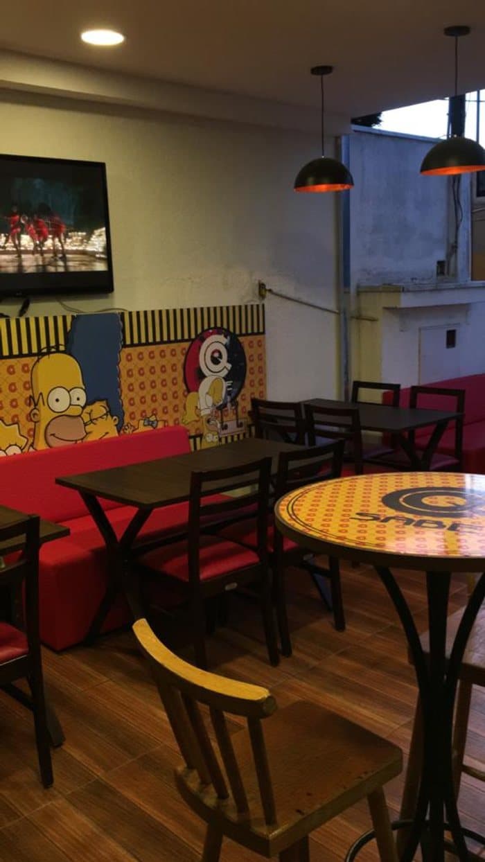 Interior da casa, mesas e ambiente descontraído do CQ Sabe Lanches